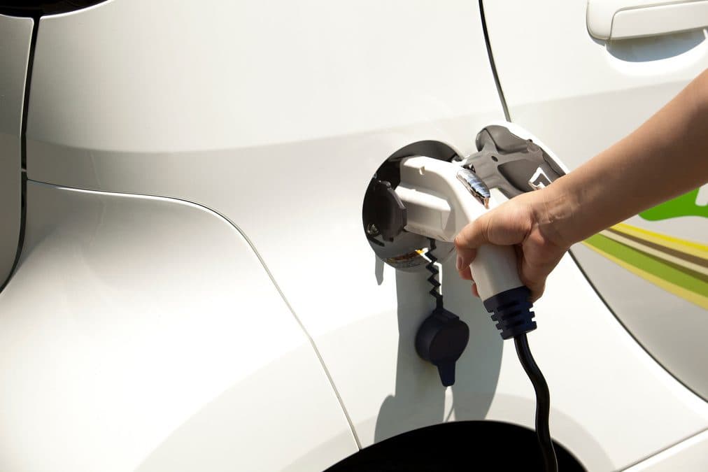 Carro elétrico sendo carregado, representando o futuro mais verde da frota Liga Coop
